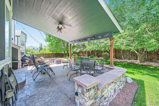 view of patio with ceiling fan, an outdoor fire pit, area for grilling, and a fenced backyard