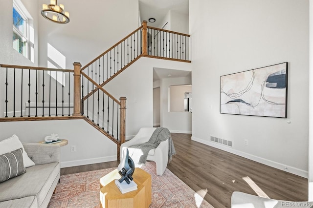 living room with a chandelier, visible vents, stairway, and wood finished floors