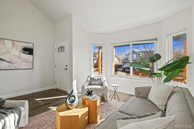 living room featuring lofted ceiling, baseboards, and wood finished floors