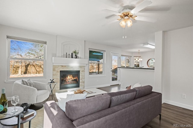 living area with a fireplace, dark wood finished floors, a ceiling fan, and baseboards