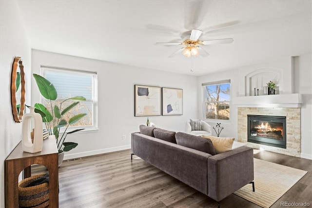 living room with a ceiling fan, baseboards, wood finished floors, and a glass covered fireplace