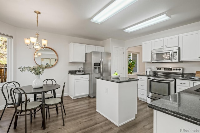 kitchen featuring appliances with stainless steel finishes, dark wood-style flooring, white cabinets, and a center island