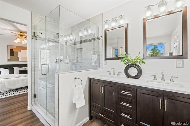 full bath featuring double vanity, ensuite bathroom, a stall shower, a sink, and wood finished floors