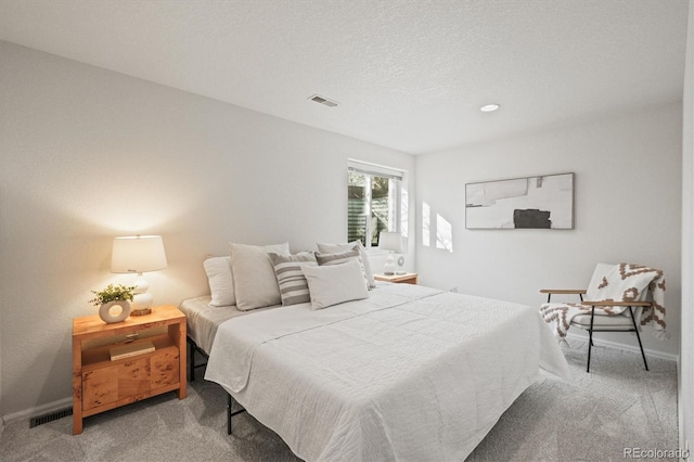 carpeted bedroom featuring baseboards, visible vents, and a textured ceiling