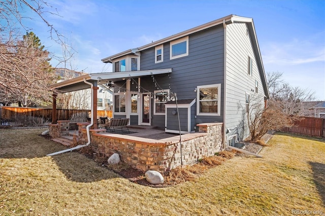 rear view of property with a yard, a patio area, and a fenced backyard