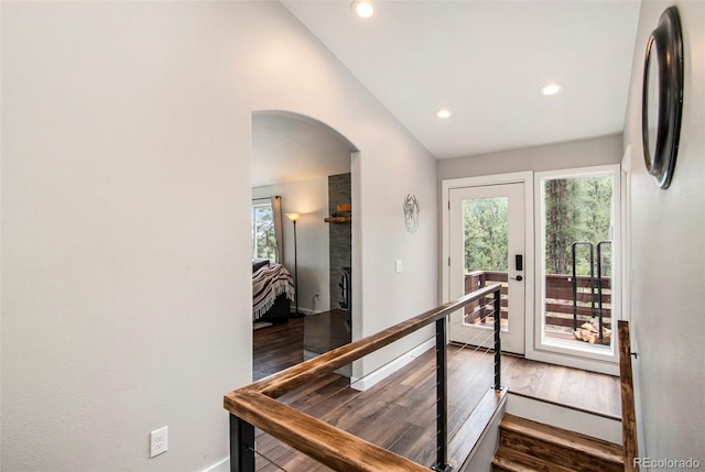 hall with baseboards, arched walkways, lofted ceiling, wood finished floors, and recessed lighting