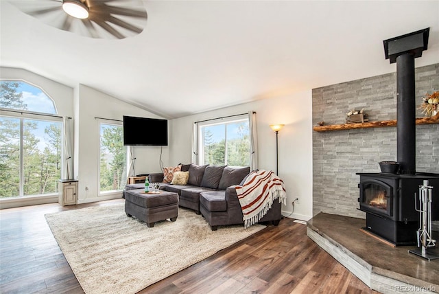 living room with vaulted ceiling, dark hardwood / wood-style flooring, ceiling fan, and a wood stove