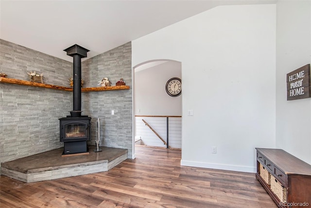 unfurnished living room with a wood stove, vaulted ceiling, and hardwood / wood-style floors