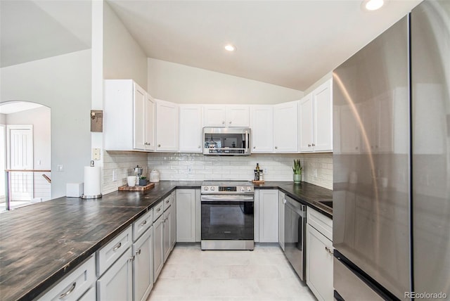 kitchen featuring lofted ceiling, light tile patterned flooring, appliances with stainless steel finishes, and tasteful backsplash