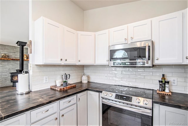 kitchen featuring a wood stove, stainless steel appliances, and white cabinetry