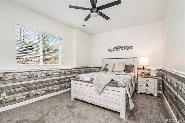 carpeted bedroom featuring ceiling fan and wooden walls