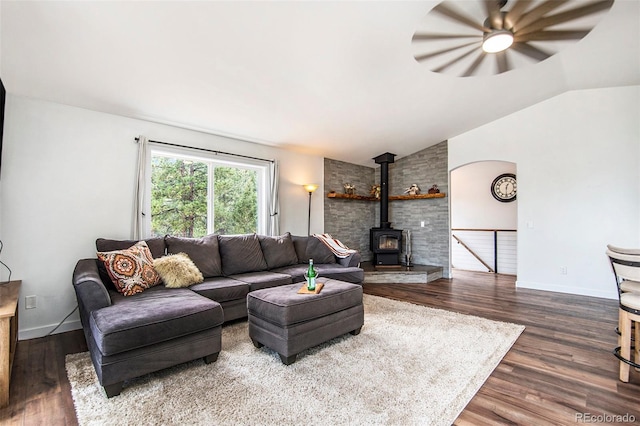 living room with a wood stove, vaulted ceiling, ceiling fan, and dark wood-type flooring