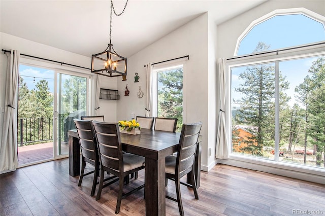 dining room with wood-type flooring, lofted ceiling, and an inviting chandelier