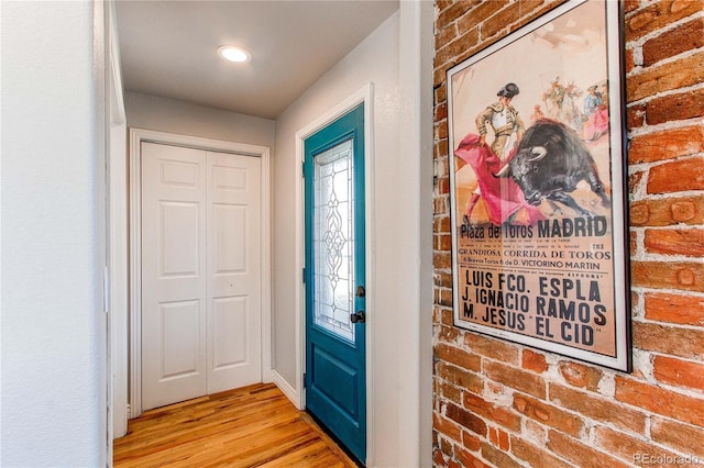 entrance foyer with light wood-style flooring and brick wall