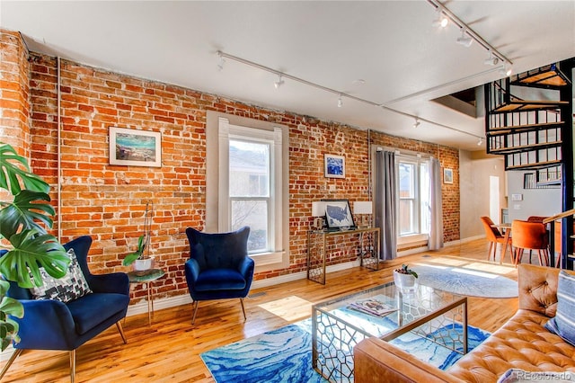 living room with hardwood / wood-style floors, brick wall, and rail lighting