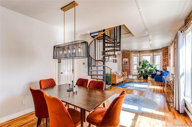 dining room with light wood finished floors, stairway, track lighting, and baseboards