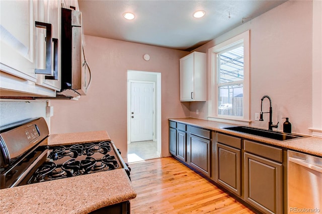 kitchen with recessed lighting, light wood-style flooring, appliances with stainless steel finishes, white cabinets, and a sink