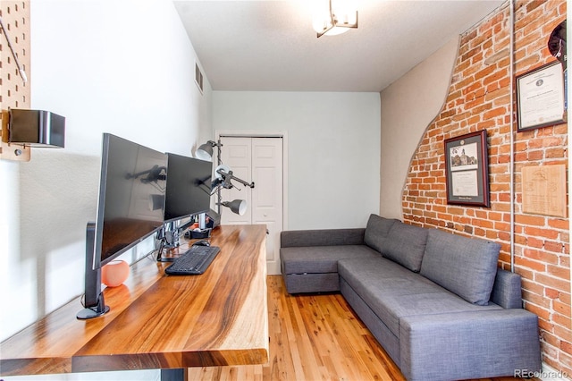 living room featuring visible vents, brick wall, and wood finished floors