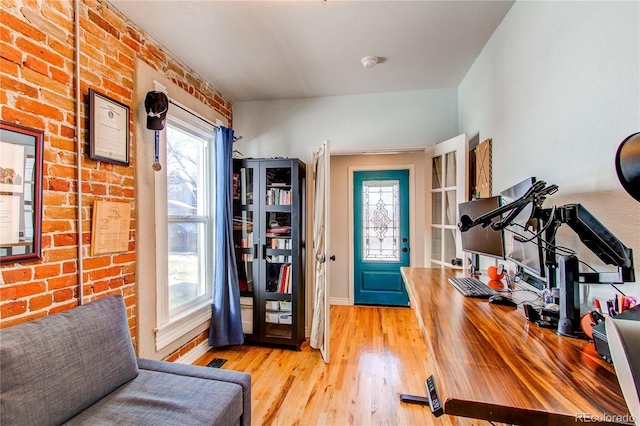 foyer featuring visible vents, brick wall, and wood finished floors