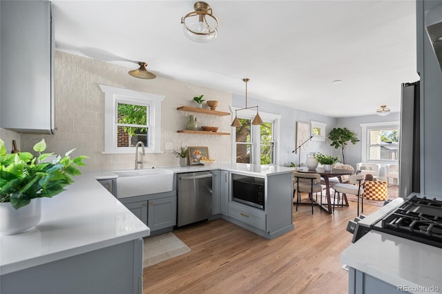 kitchen with stainless steel dishwasher, a sink, built in microwave, gray cabinets, and light countertops