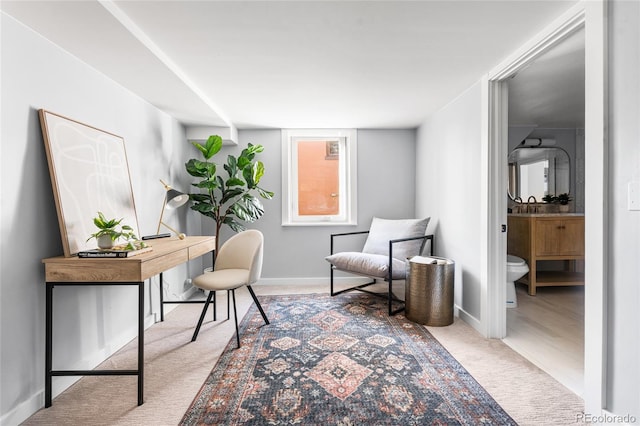 carpeted office space with baseboards and a sink
