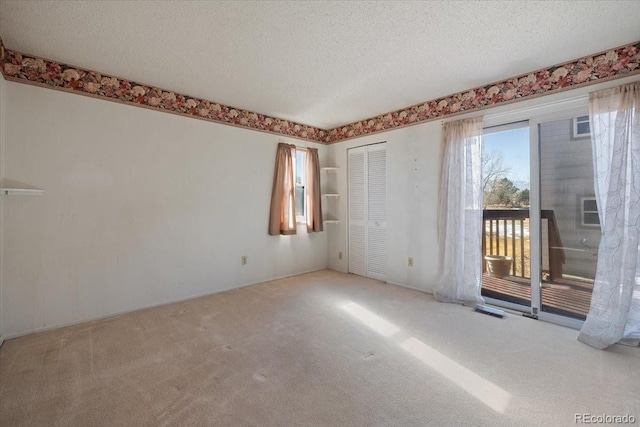 carpeted empty room featuring a textured ceiling