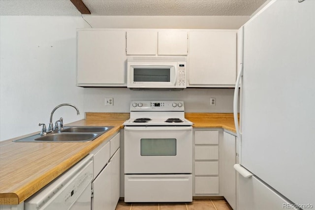 kitchen featuring white appliances, light tile patterned floors, sink, and white cabinets