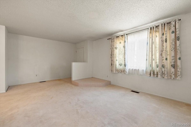 carpeted empty room featuring a textured ceiling