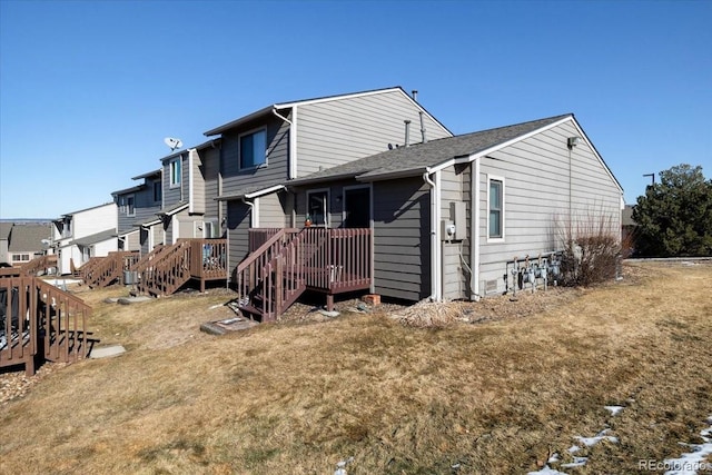 back of house featuring a wooden deck and a lawn