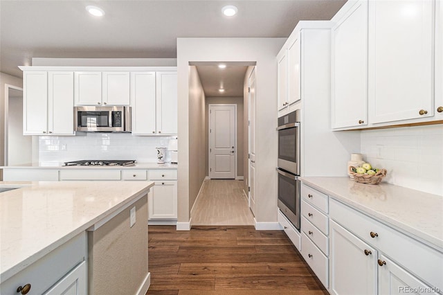 kitchen featuring light stone countertops, white cabinetry, appliances with stainless steel finishes, and dark hardwood / wood-style flooring