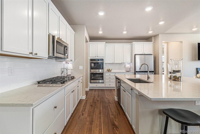 kitchen featuring white cabinetry, stainless steel appliances, dark hardwood / wood-style floors, light stone counters, and sink