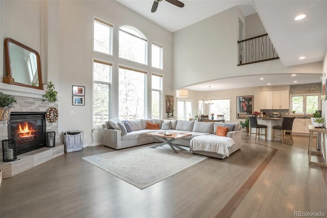 10773 Cougar Rdg, Lone Tree, CO 80124 - living area featuring a high ceiling, light wood-style floors, a fireplace, plenty of natural light, and a ceiling fan