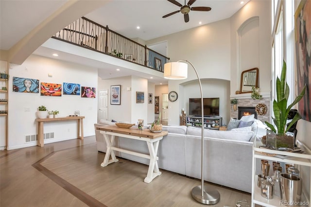 10773 Cougar Rdg, Lone Tree, CO 80124 - living room featuring a ceiling fan, wood finished floors, a fireplace, a high ceiling, and recessed lighting