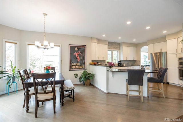 10773 Cougar Rdg, Lone Tree, CO 80124 - kitchen featuring appliances with stainless steel finishes, a chandelier, tasteful backsplash, a peninsula, and white cabinets