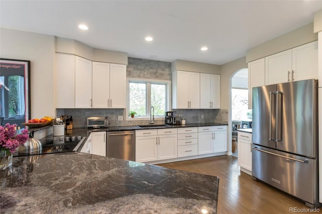 10773 Cougar Rdg, Lone Tree, CO 80124 - kitchen featuring appliances with stainless steel finishes, a sink, dark stone countertops, decorative backsplash, and white cabinets
