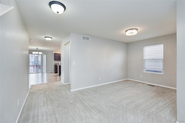 carpeted empty room with a notable chandelier