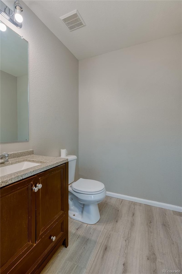 bathroom with wood-type flooring, vanity, and toilet