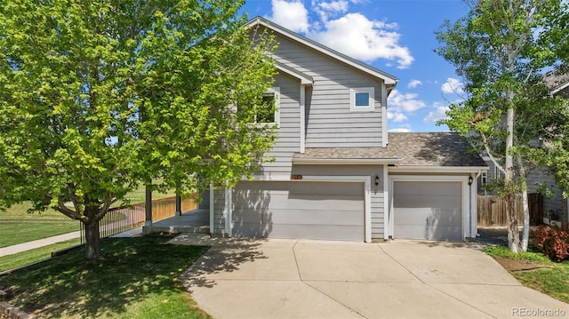 view of front facade with an attached garage, driveway, and fence