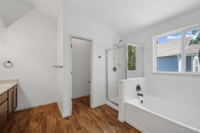 bathroom featuring vanity, a shower stall, wood finished floors, a bath, and baseboards