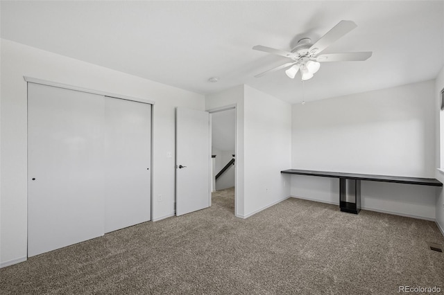 unfurnished bedroom with carpet, a closet, a ceiling fan, and baseboards