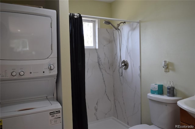 bathroom featuring stacked washer and clothes dryer, toilet, and a marble finish shower