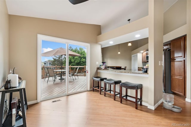 3390 S Ensenada Way, Aurora, CO 80013 - kitchen featuring vaulted ceiling, light wood-style flooring, a kitchen breakfast bar, stainless steel microwave, and light countertops