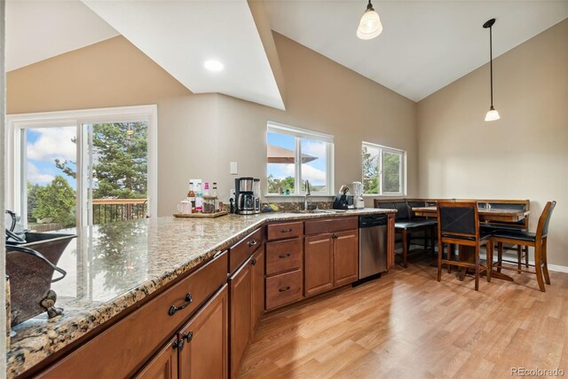 3390 S Ensenada Way, Aurora, CO 80013 - kitchen featuring stainless steel dishwasher, brown cabinetry, light wood-style flooring, light stone counters, and high vaulted ceiling