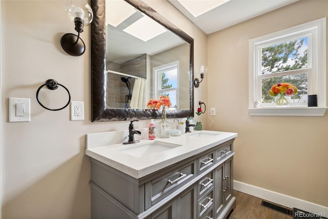 3390 S Ensenada Way, Aurora, CO 80013 - bathroom featuring plenty of natural light, double vanity, wood finished floors, and a shower with shower curtain