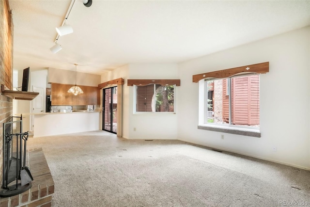 5010 Sunsuite Trl, Colorado Springs, CO 80917 - unfurnished living room with carpet, track lighting, a chandelier, and a fireplace