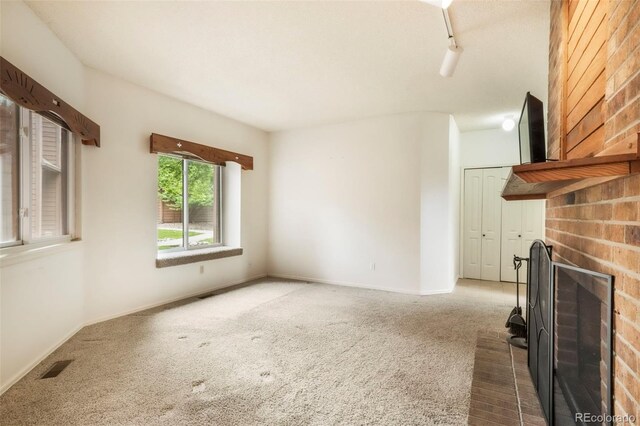 5010 Sunsuite Trl, Colorado Springs, CO 80917 - unfurnished living room with a brick fireplace, carpet flooring, and baseboards