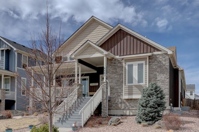 craftsman-style home featuring stone siding, covered porch, and board and batten siding