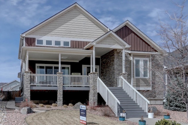 craftsman house with a porch, stone siding, board and batten siding, and stairs