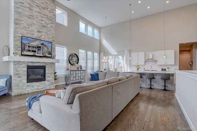 living area with baseboards, dark wood-type flooring, and a stone fireplace