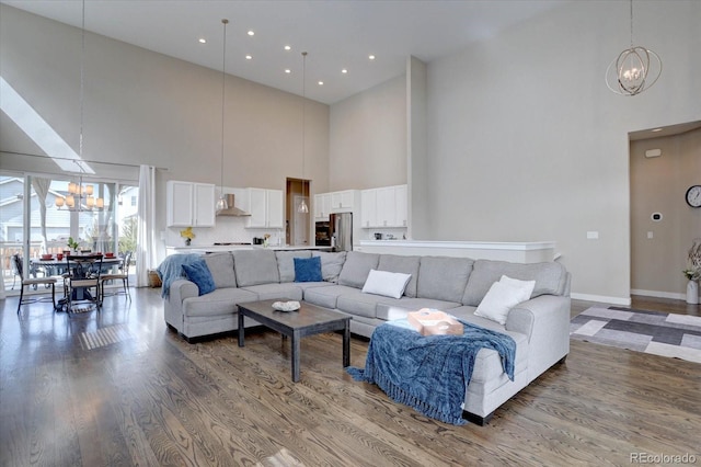 living room with an inviting chandelier, a high ceiling, wood finished floors, and baseboards